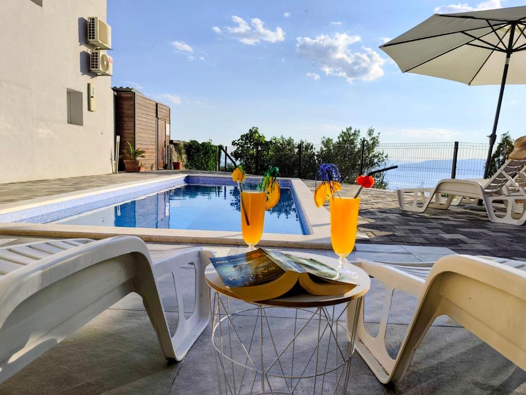 a table with drinks on it next to a swimming pool at Villa TOP HILL - Private Pool & Jacuzzi in Makarska