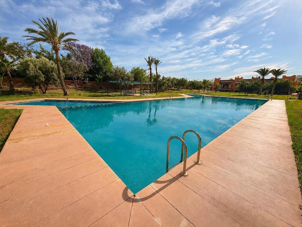 a large swimming pool with blue water and palm trees at Elegant, quiet villa in Marrakesh