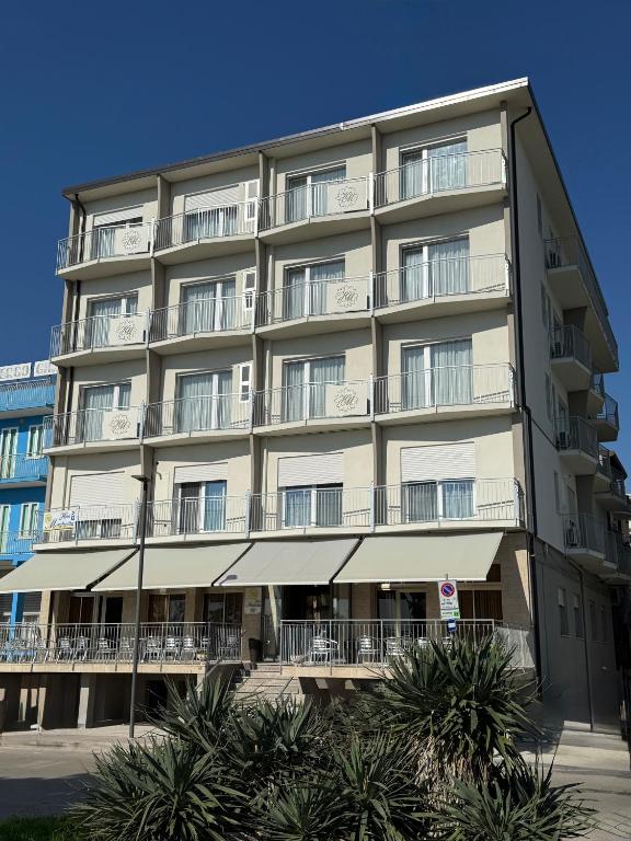 a large apartment building with balconies and palm trees at Hotel Margherita in Sottomarina