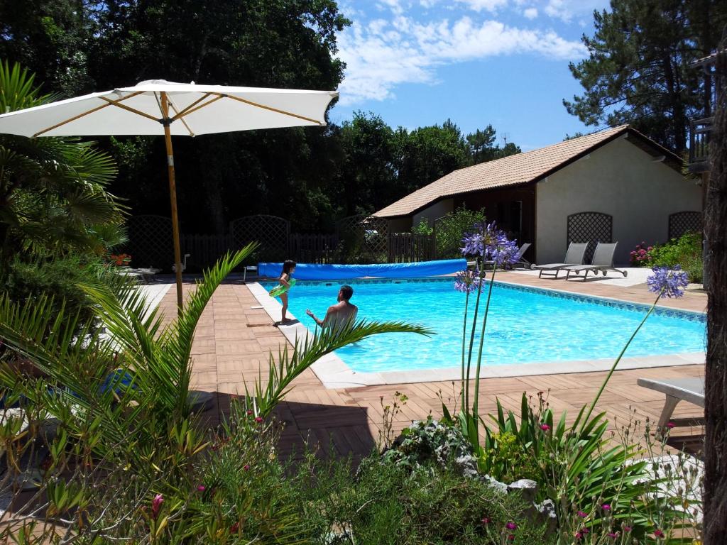 dos niños jugando en una piscina con sombrilla en Village Club Dunea, en Soustons
