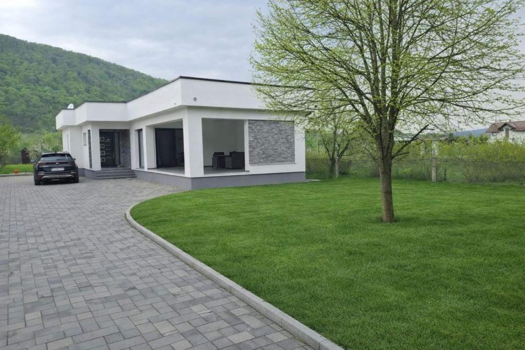 a white house with a car parked in a yard at Villa Una-Adi-Ela in Bihać