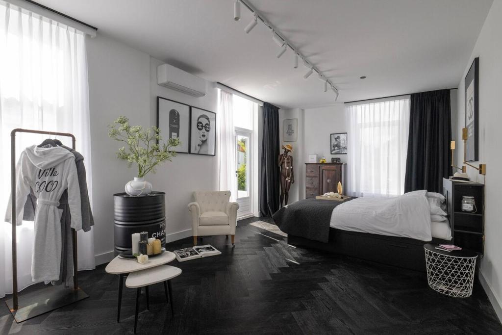 a bedroom with a bed and a chair in it at Villa COCO Chanel Kamer in Noordwijk