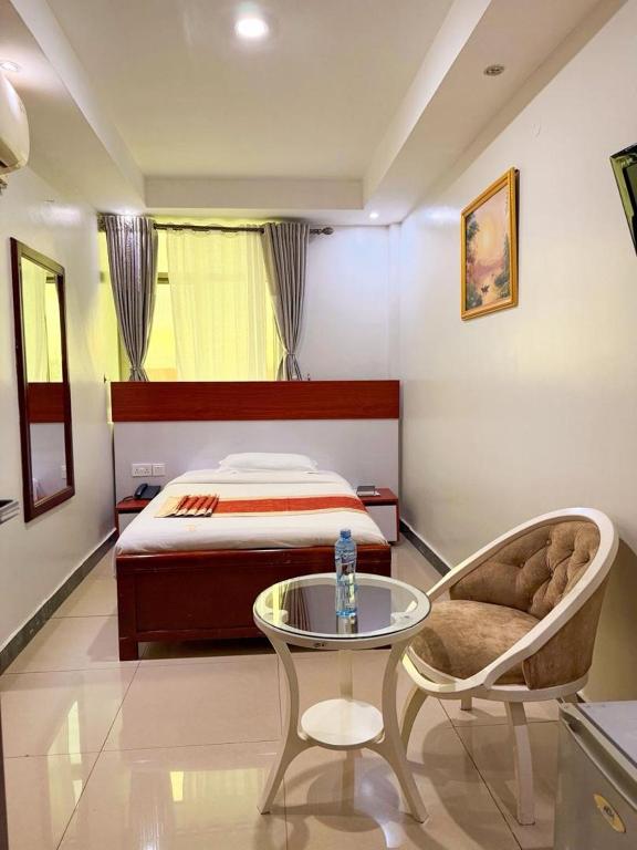 a bedroom with a bed and a table and a chair at La Grande Hotel in Kampala