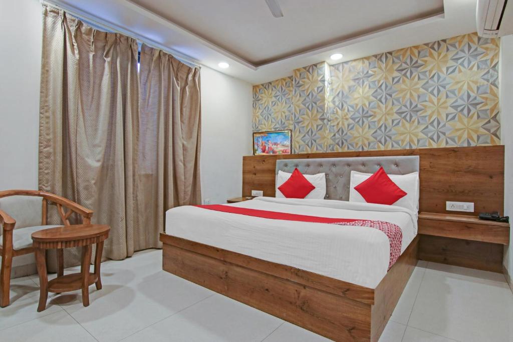 a bedroom with a large bed with red pillows at Hotel O Avi Suites in New Delhi