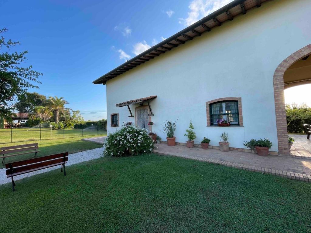 a white building with a bench in a yard at Casale Country Chic- Sabaudia in Borgo Isonzo