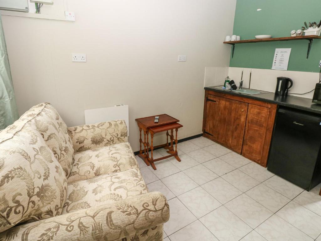 a living room with a couch and a kitchen at Cabin No 15 - Salt and Fern Cabins in Port Talbot