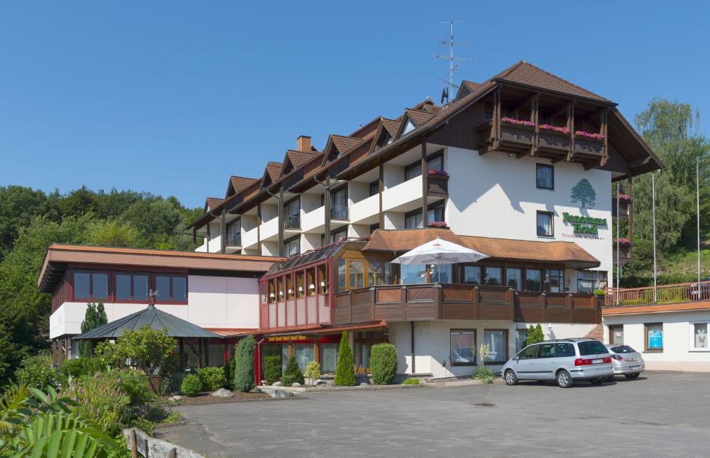 a large hotel with cars parked in a parking lot at PANORAMA Hotel Heimbuchenthal in Heimbuchenthal