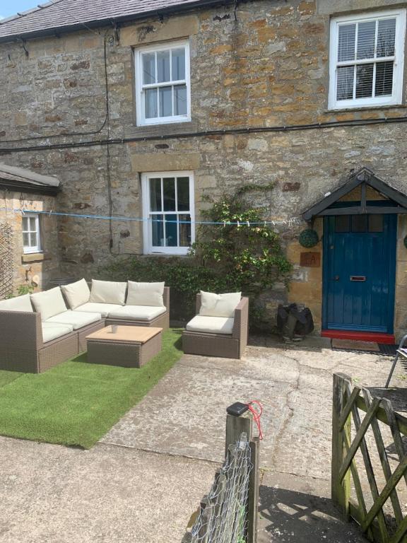 a patio with couches in front of a building at Low Houses Hadrians Wall in Stagshaw Bank