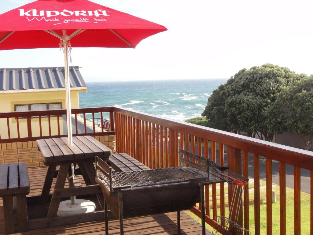 a wooden deck with a picnic table and an umbrella at Berg En See in Kleinmond