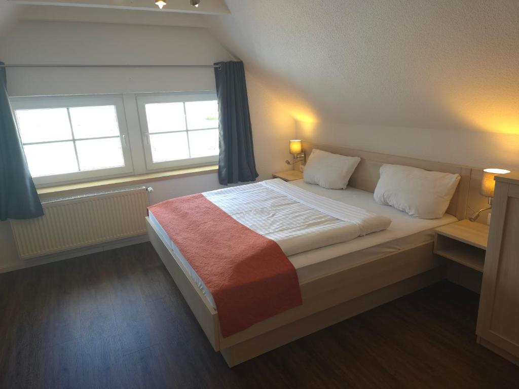 a bedroom with a large bed with two windows at Hotel Up´n Diek in Dangast