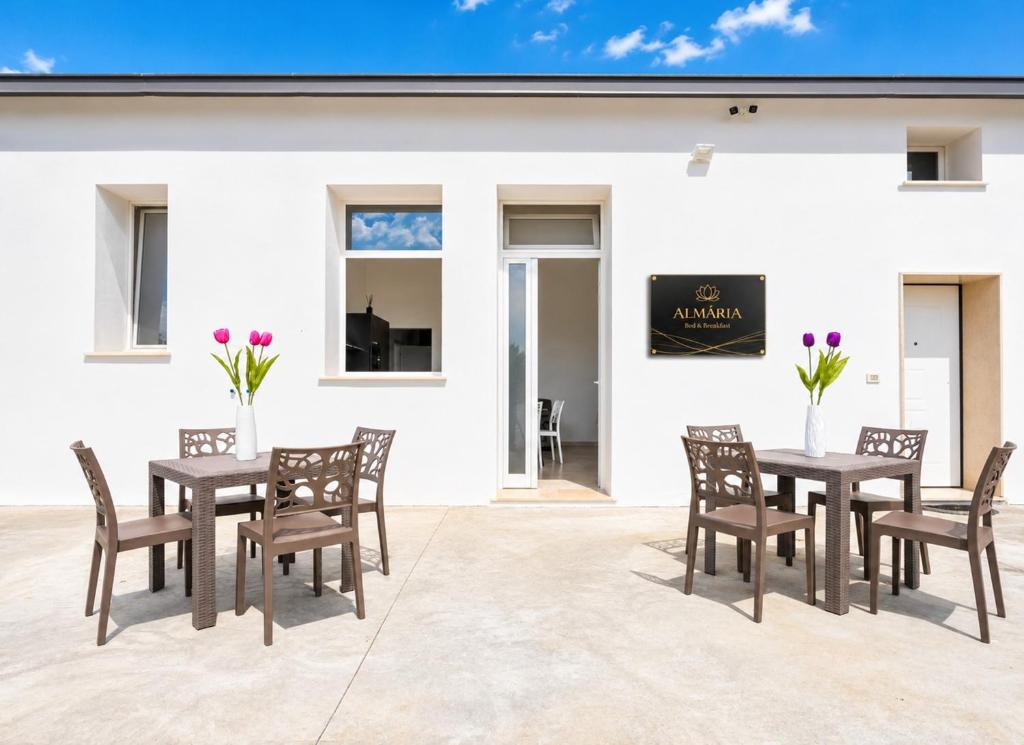 a patio with tables and chairs and a white building at Almària - Rooms e Garden in Nardò