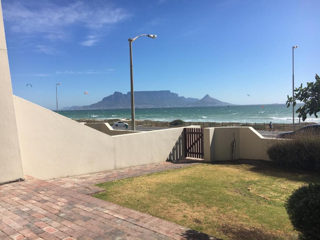 a white fence with the beach in the background at Beachfront Apartment at Malata Beach in Blouberg in Bloubergstrand