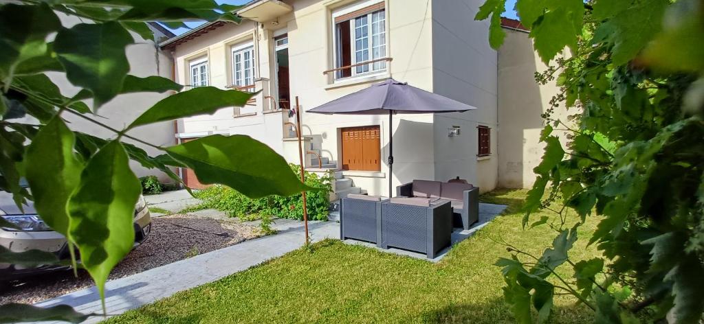 an umbrella in the yard of a house at Métro - Sac à dos - Dodo Chez Léontine 2 chambres Parking Wifi in Colombes