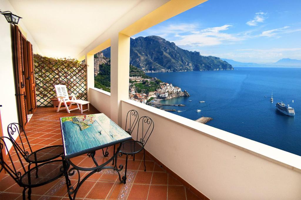 balcón con mesa, sillas y vistas al agua en Casa Nancy, en Amalfi