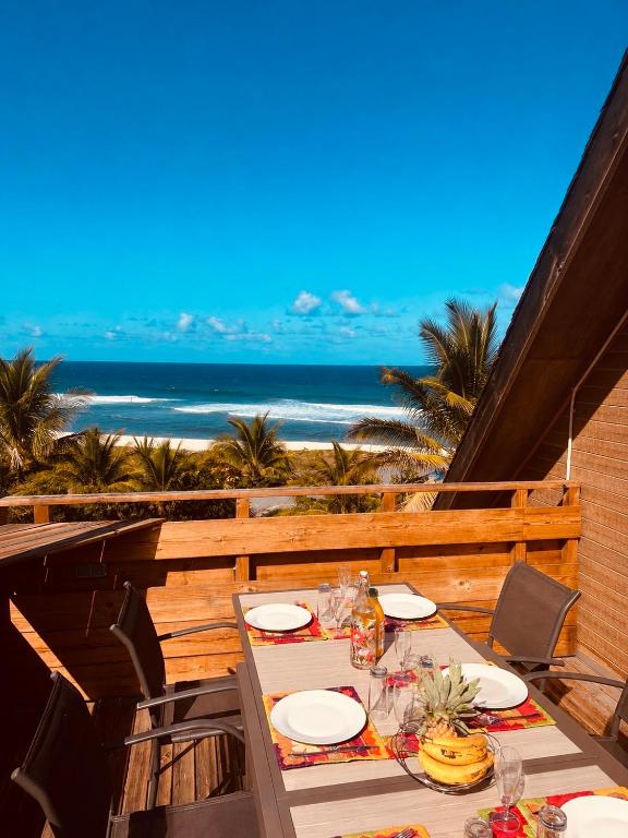 a table on a balcony with a view of the beach at Grand Appartement - Pétrel 2 in Trois Bassins