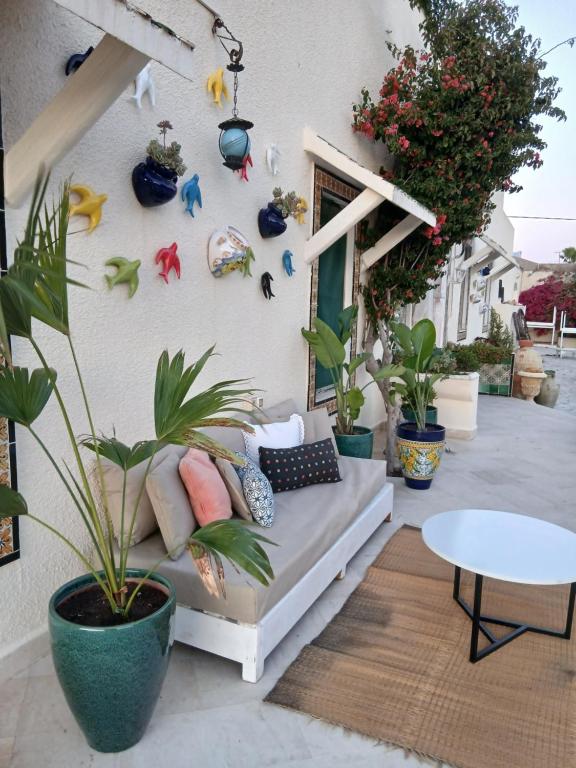 a patio with a couch and plants on a wall at Darelkhir in Tazarka