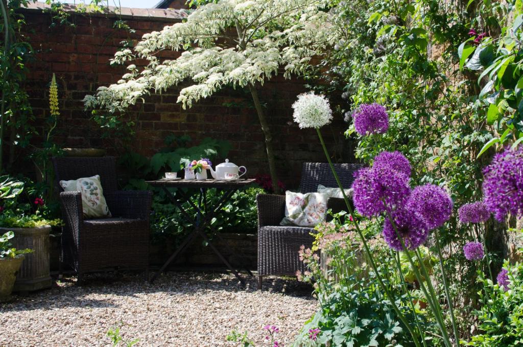 um jardim com duas cadeiras e uma mesa com flores roxas em The Hollies Bed and Breakfast em Uppingham