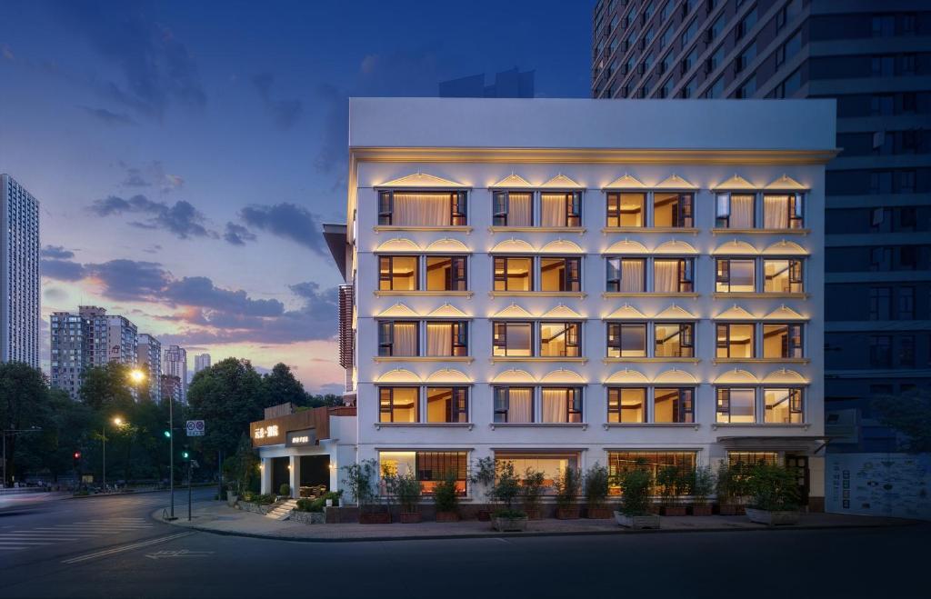 a tall white building with lights on at Chengdu Yunduo Bieyuan 云朵 Hotel in Chengdu