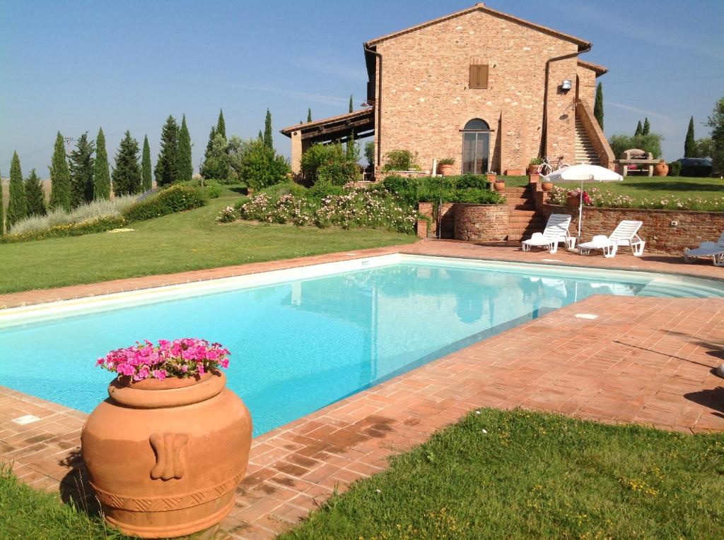 a swimming pool with a pot of flowers next to a house at Podere Fornaci in Asciano