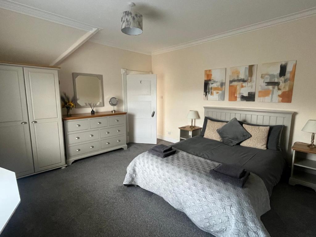 a bedroom with a bed and a dresser and a mirror at Dun-Niall Apartment in Oban