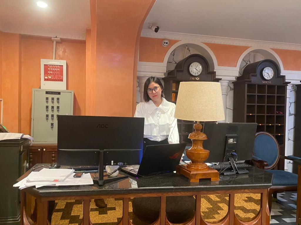 a woman standing behind a desk with two laptops at SAPA DEBOUTIQUE Hotel in Sapa