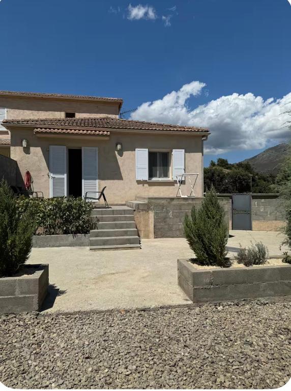 a house with stairs and a house with mountains in the background at Mini villa in Corte