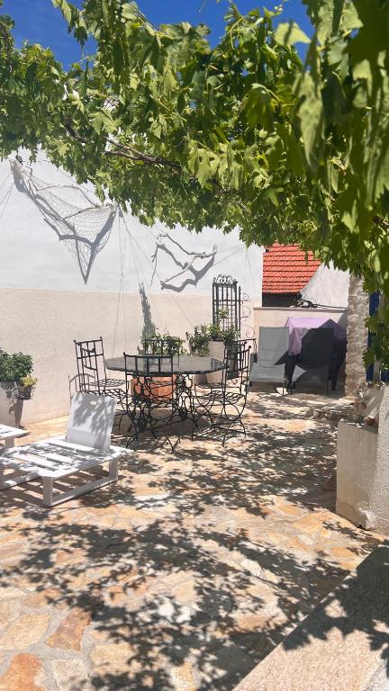 a patio with a table and chairs under a tree at VILLA MOST Tisno in Tisno