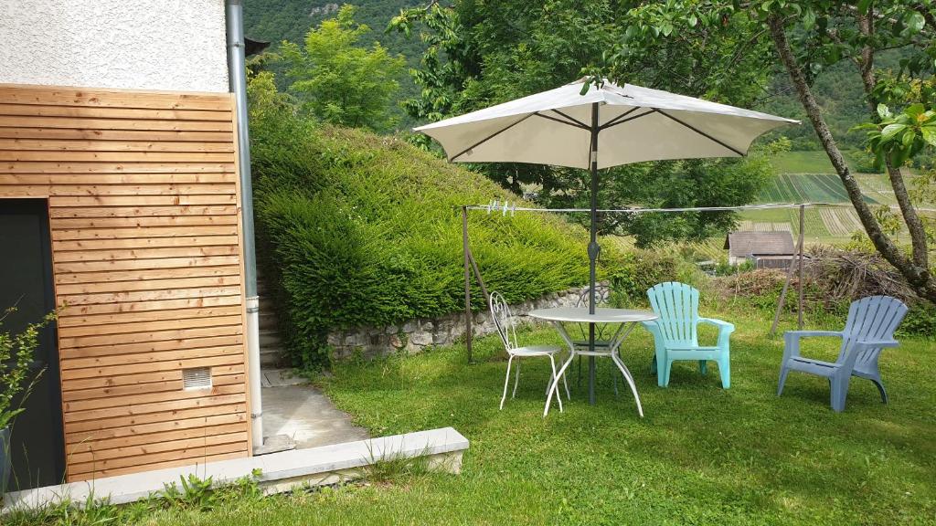 a table and chairs with an umbrella in a yard at Studio au calme - rez de jardin in Chignin