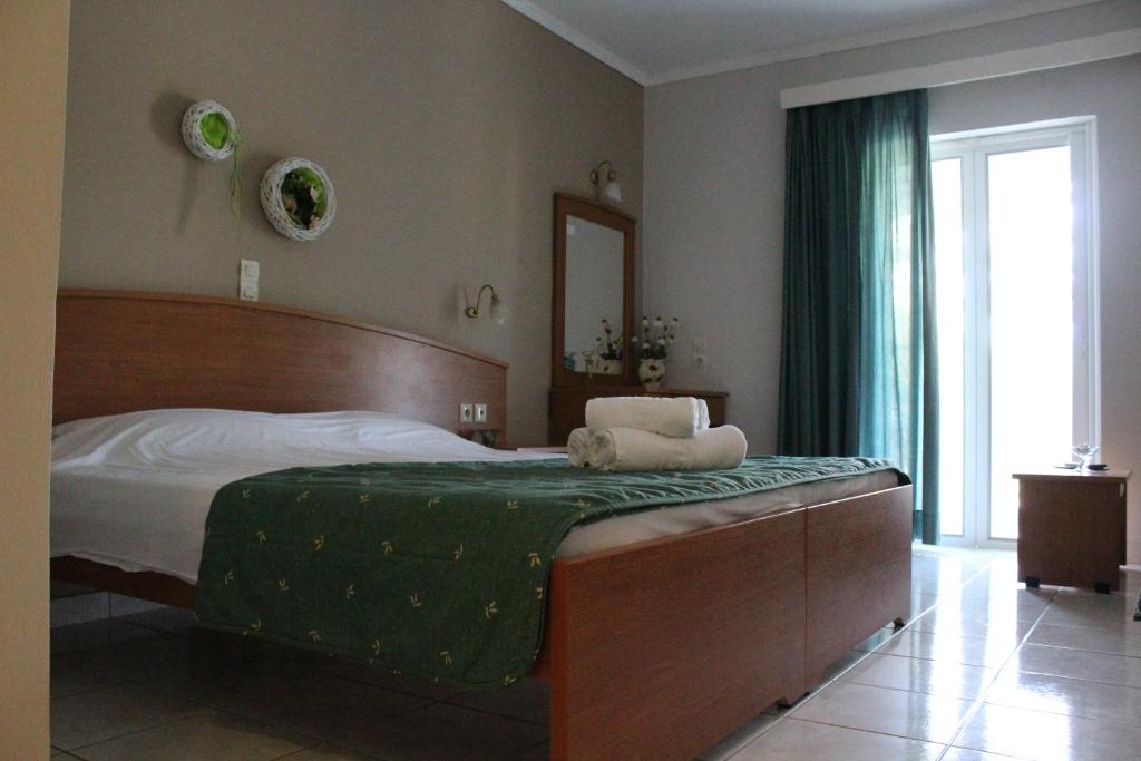 a bedroom with a large bed with a green blanket at Smile's Studios in Tsilivi