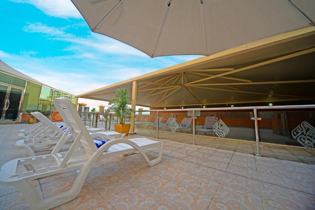 a group of lounge chairs and an umbrella on a patio at Emirates Stars Hotel Apartments Dubai in Dubai