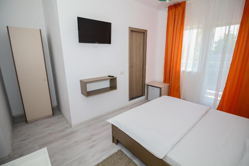 a bedroom with two beds and a tv on the wall at Hotel Atlantis in Eforie Nord