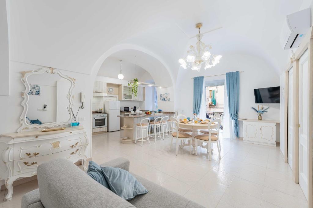 a white living room with a table and a kitchen at Domus Almaré in Minori