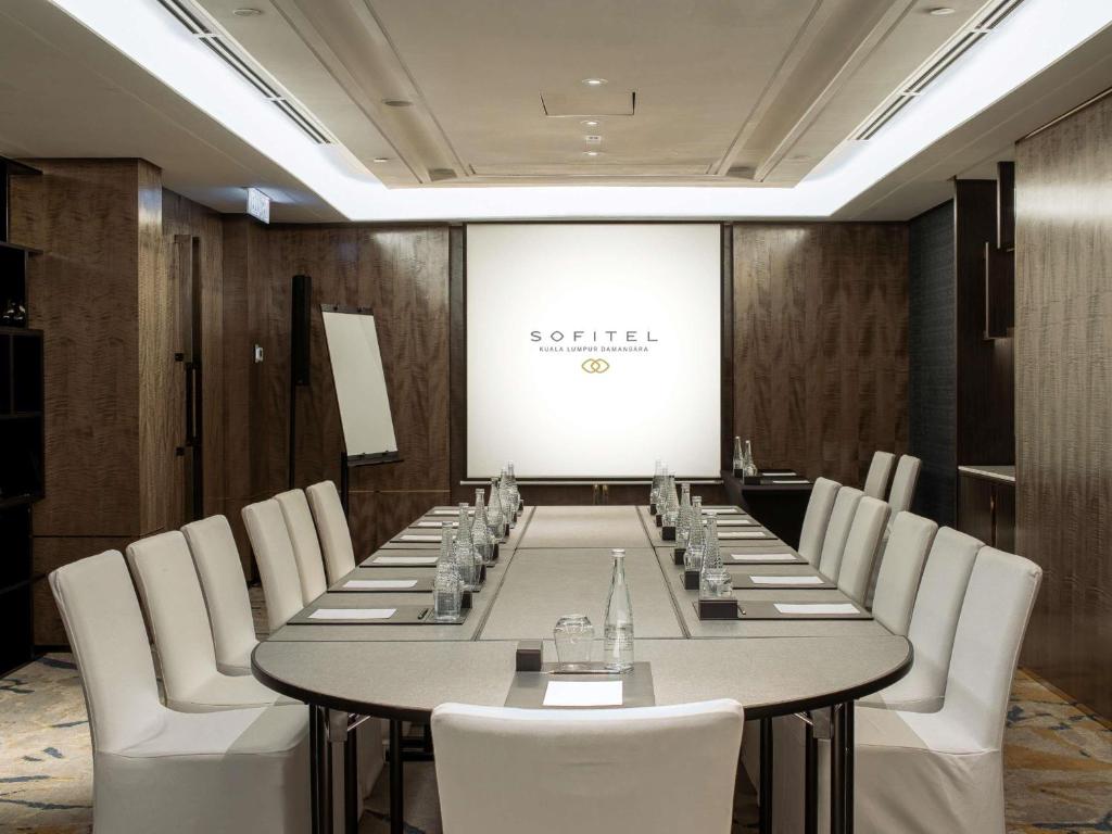 A boardroom set for a presentation, with a long table and white chairs.