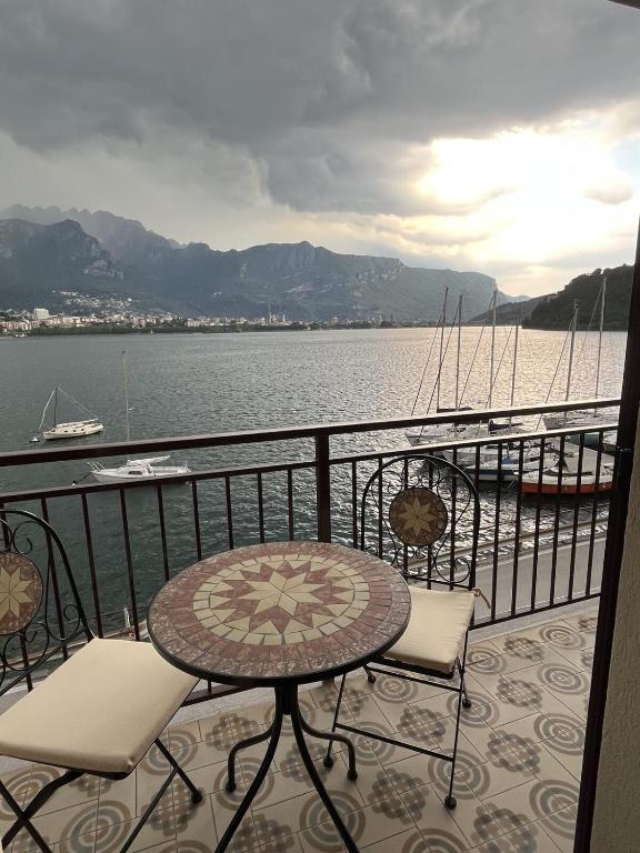 a balcony with a table and chairs next to the water at Casa delle vele in Valmadrera