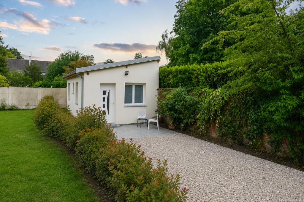 a small white house with a chair in a garden at Le Clos de Vaires in Vaires-sur-Marne