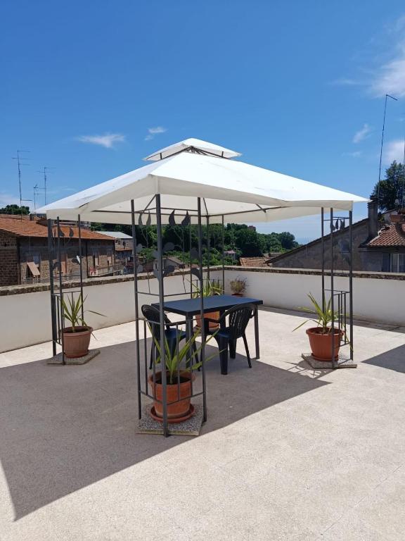 a table and chairs under a white umbrella on a roof at La terrazza al 29 in Carbognano