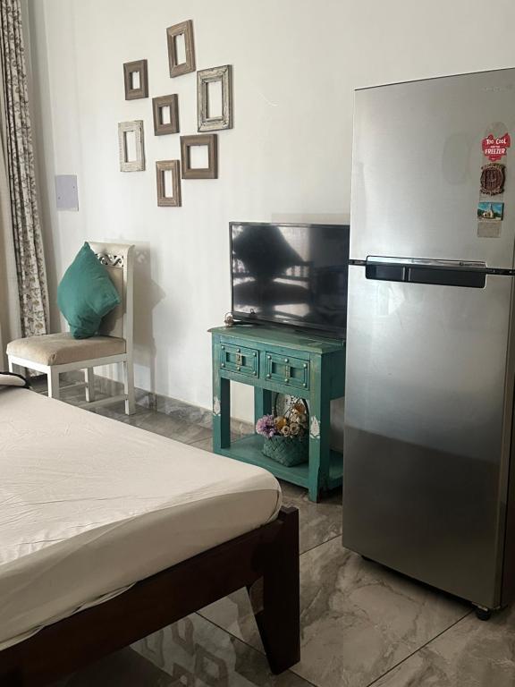 a room with a refrigerator and a tv and a table at Beyond the city peaks in Kangra Airport