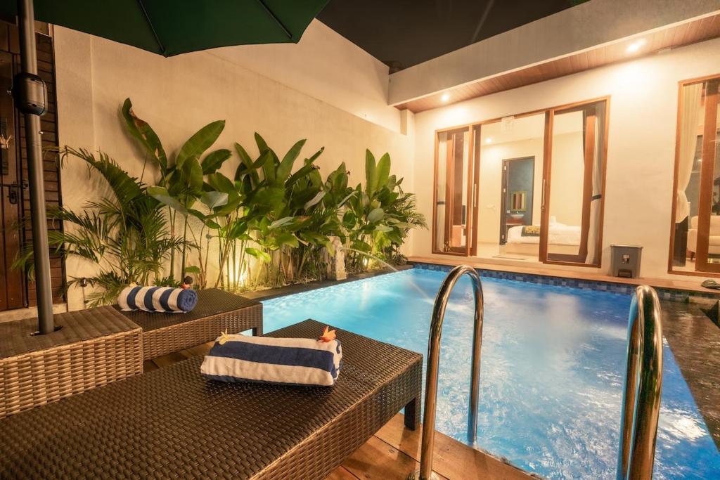 a swimming pool with a table and a chair next to it at Sawitri Ubud Villas in Blahbatu