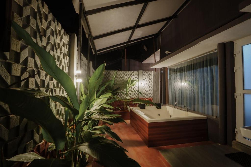 a bathroom with a large plant and a bath tub at Nitz the loft in Pondicherry