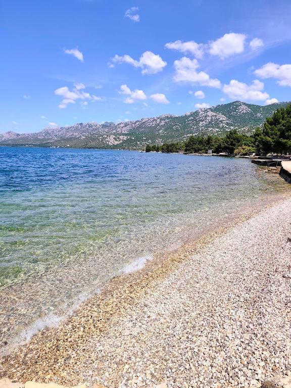 a beach with blue water and mountains in the background at Kuća za odmor "Gabriel" in Rovanjska