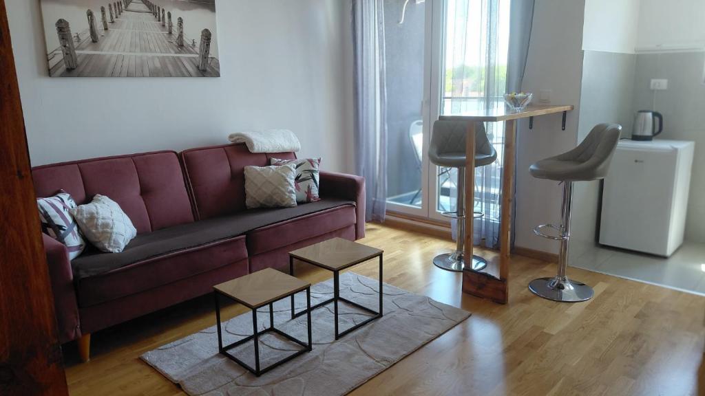 a living room with a purple couch and a stool at Cozy Studio-Self check in in Beograd