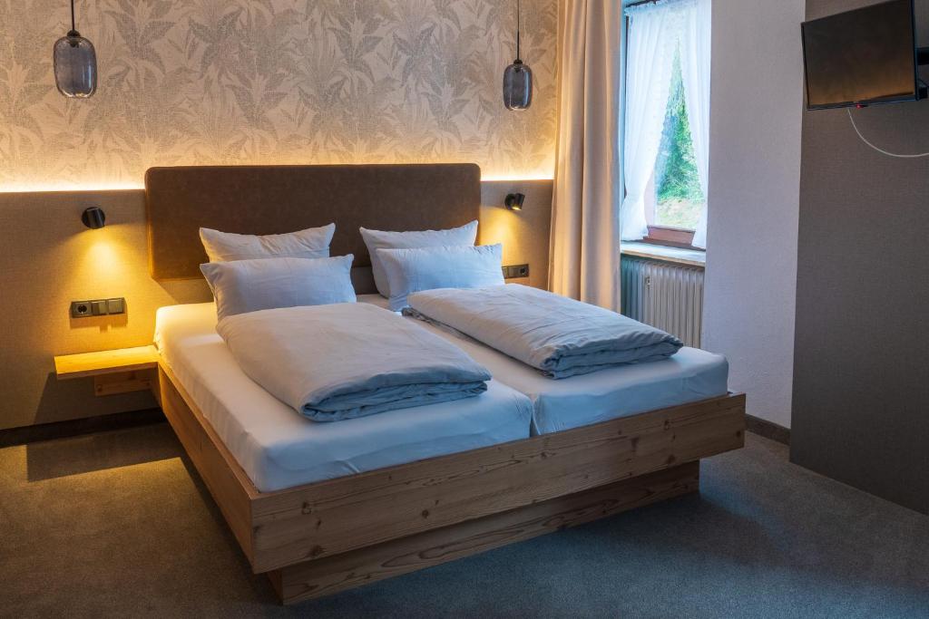 a bedroom with a bed with white pillows and a window at Hotel Restaurant St. Germanshof in Bobenthal
