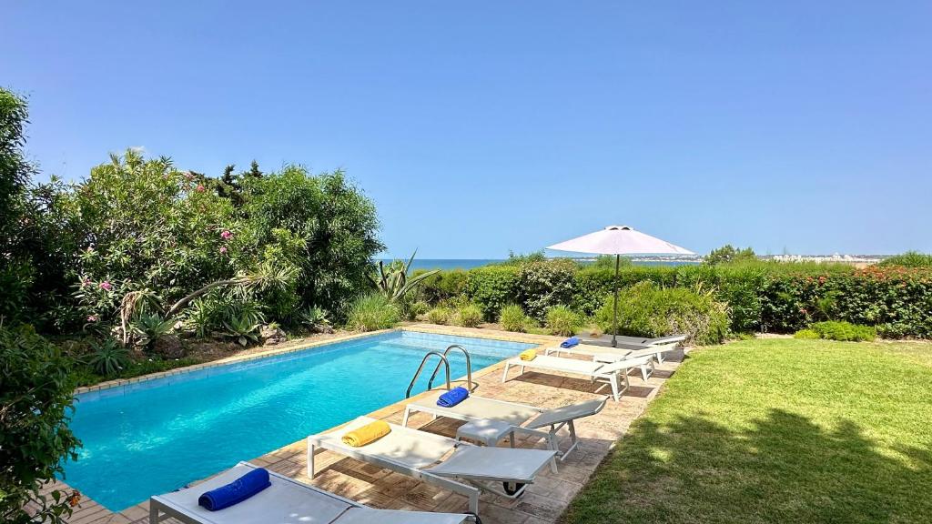 a swimming pool with tables and chairs and an umbrella at Dunas - Private Pool - 8 Guests - Albufeira in Albufeira