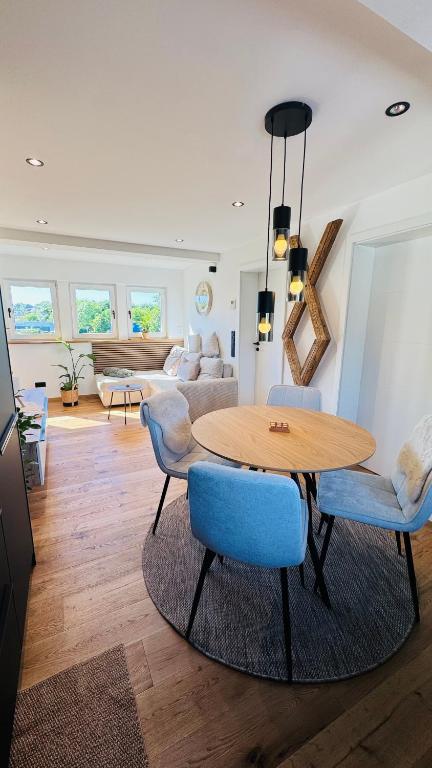 a living room with a wooden table and blue chairs at Klimatisierte Komfort-Eifel-Ferienwohnung Mechernich, Obergartzem, Satzvey - nahe Krewelshof, Burg Satzvey & Phantasialand in Mechernich