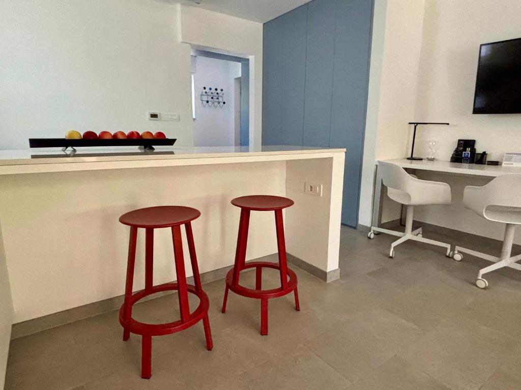 a kitchen with two red stools next to a counter at Ankaran Studio Escape in Ankaran