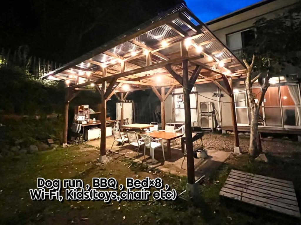a wooden pergola with a table in a yard at night at Cruise garden in Kanō