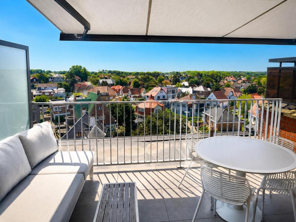a living room with a couch and a table on a balcony at Cozy Rooftop - Sint-Idesbald in Koksijde