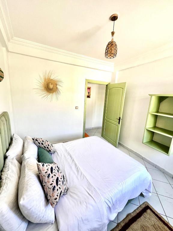 a bedroom with a white bed and a green door at Cozy Flat With Pool Near The Beach TAMRAGHT -APP13 in Tamraght Ouzdar