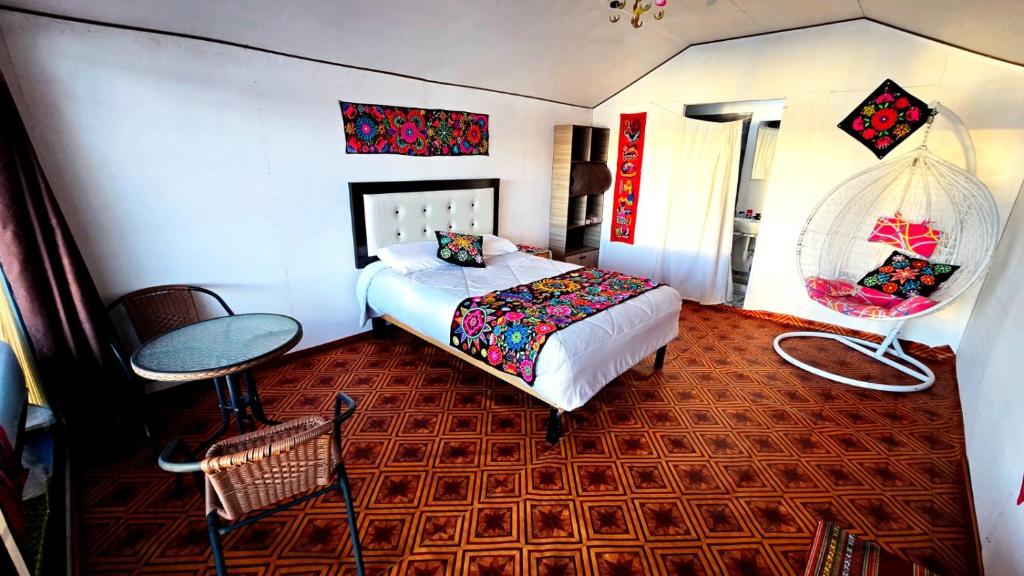 a bedroom with a bed and a table and a chair at Uros titikaka Golden Lodge in Puno