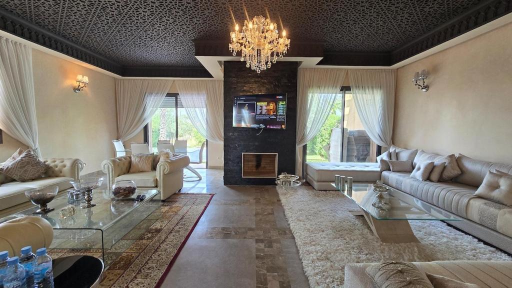 a living room with couches and a chandelier at Villa Yacout Marrakech -Private Pool in Sraghna